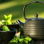 Black iron asian teapot with sprigs of mint for tea Black iron asian teapot with sprigs of mint for tea